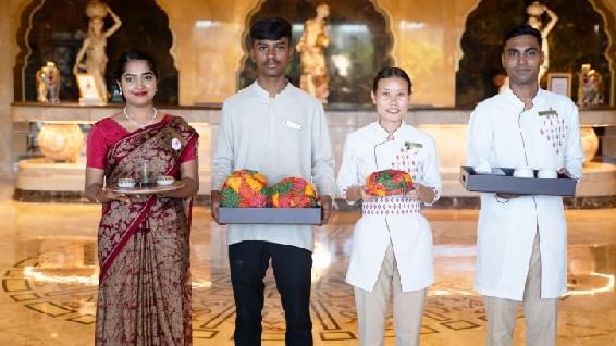 Two women and two men welcoming guests holding aarthi plates with Rajasthani hats - Kaldan Samudra Palace